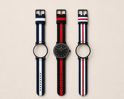 Tela Swiss Made modular watch — round black case with black dial, shown with three interchangeable nato straps in navy-white, black-red and navy-red-white
